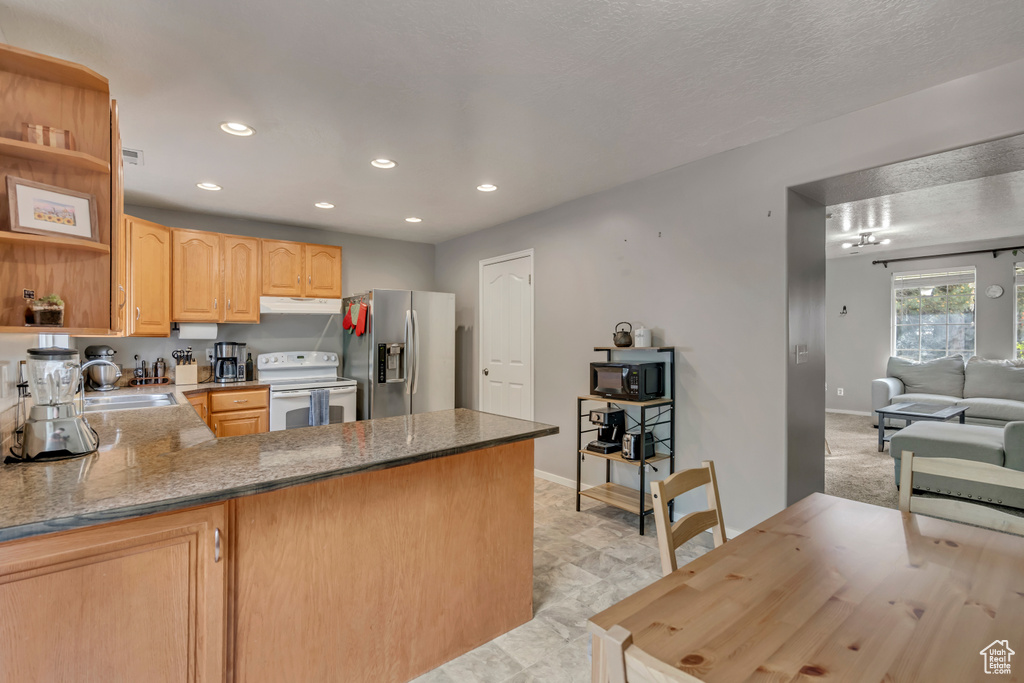 Kitchen with stainless steel fridge with ice dispenser, white range with electric cooktop, open shelves, a peninsula, and recessed lighting