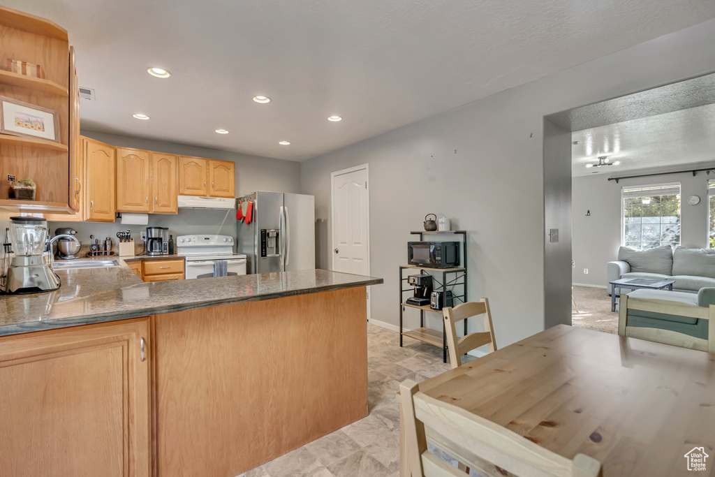 Kitchen featuring stainless steel fridge, white electric range, light brown cabinets, recessed lighting, and a peninsula