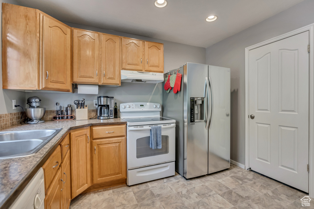 Kitchen featuring white appliances, under cabinet range hood, recessed lighting, a sink, and light countertops