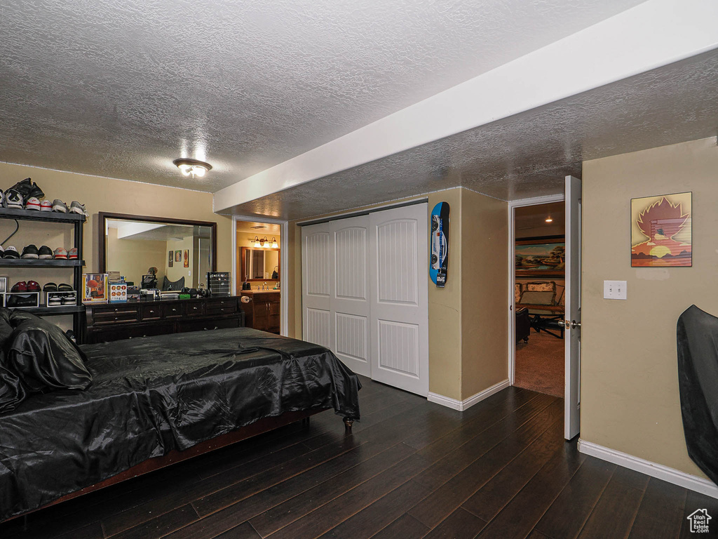 Bedroom featuring baseboards, a textured ceiling, wood finished floors, a closet, and connected bathroom