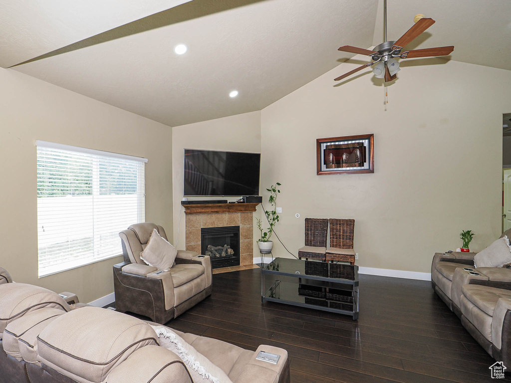 Living room with vaulted ceiling, baseboards, wood-type flooring, ceiling fan, and a fireplace