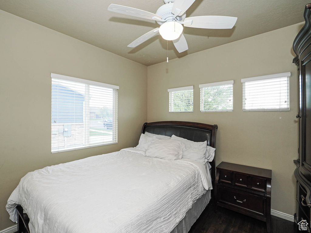 Bedroom featuring dark wood-style floors, baseboards, and a ceiling fan