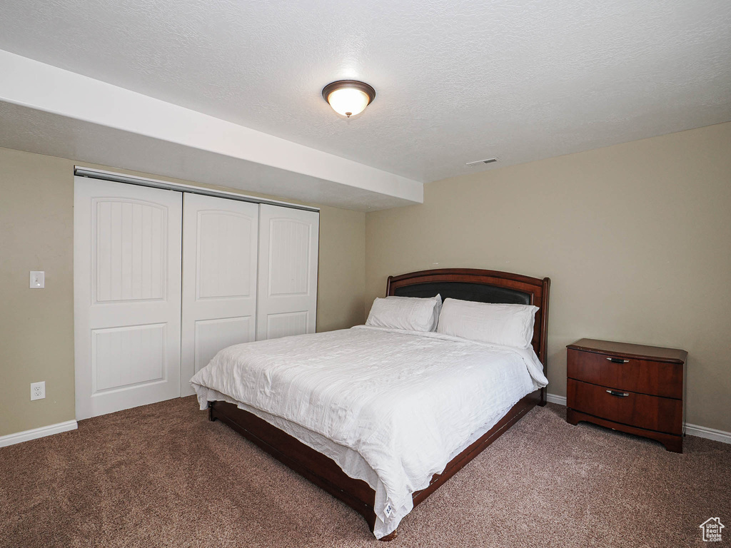 Carpeted bedroom featuring a closet, baseboards, and a textured ceiling