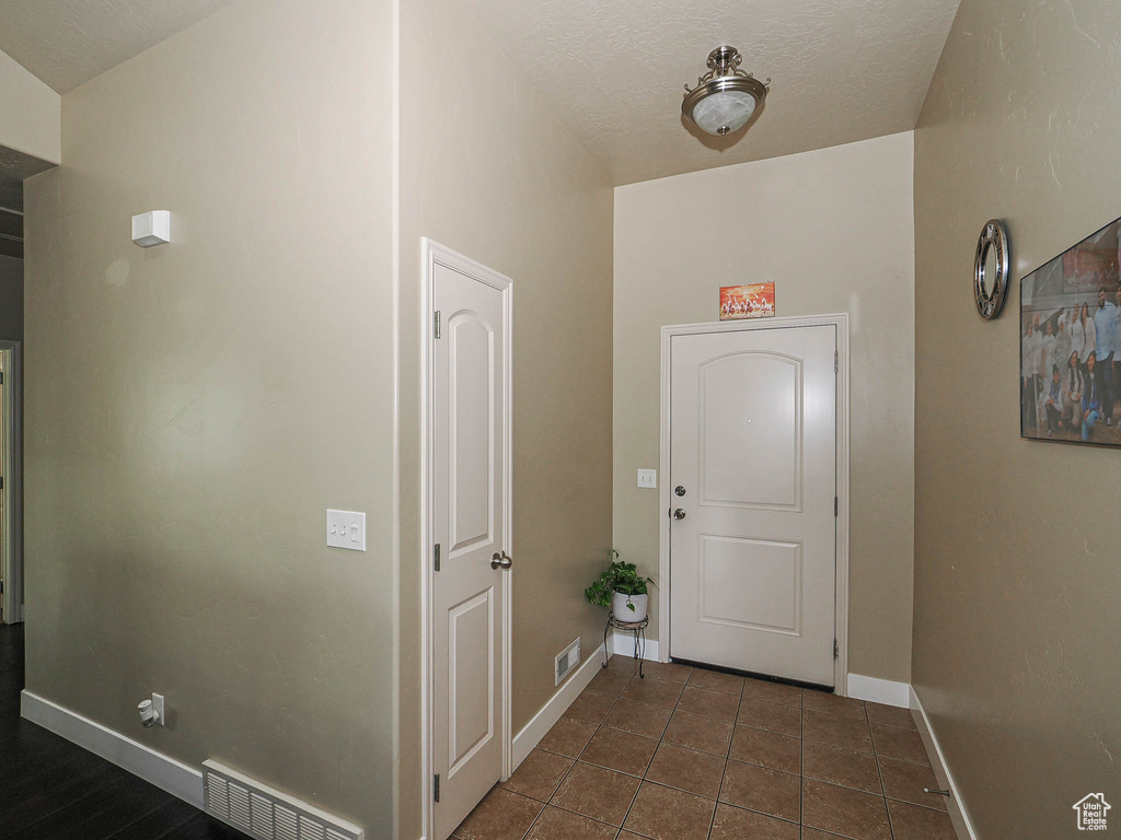 Foyer entrance with baseboards and dark tile patterned floors