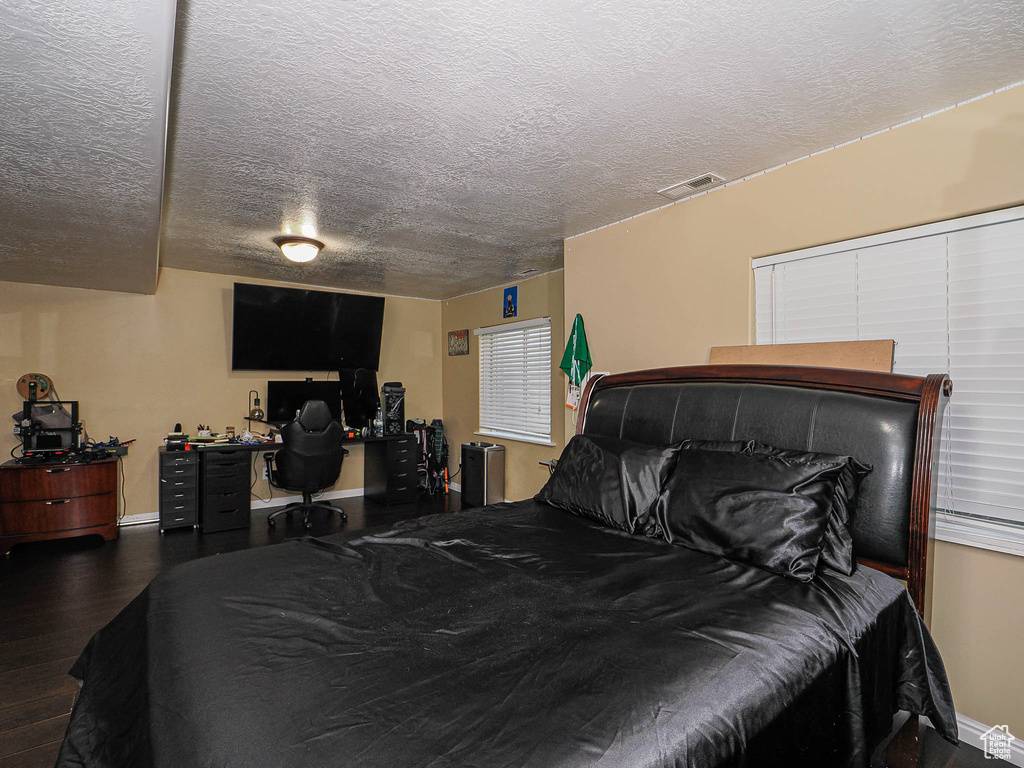 Bedroom with wood finished floors, a desk, a textured ceiling, and baseboards