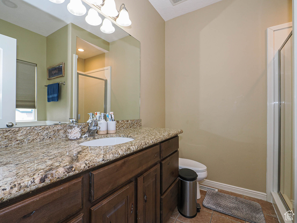 Full bathroom featuring a shower stall, tile patterned flooring, baseboards, vanity, and toilet