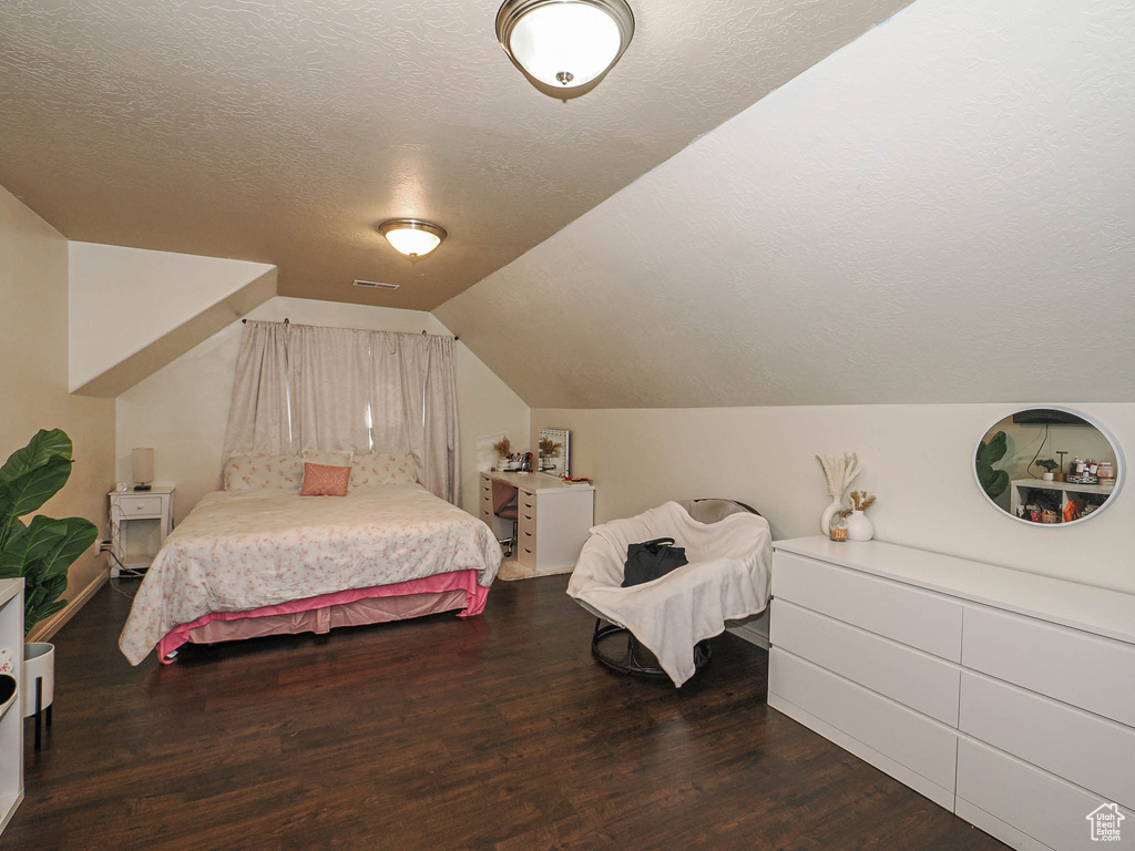 Bedroom featuring wood finished floors, a textured ceiling, and lofted ceiling