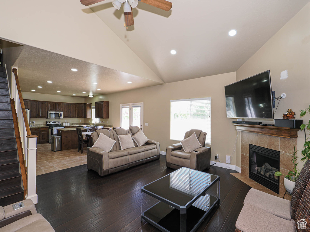 Living room featuring stairway, lofted ceiling, wood-type flooring, a fireplace, and recessed lighting