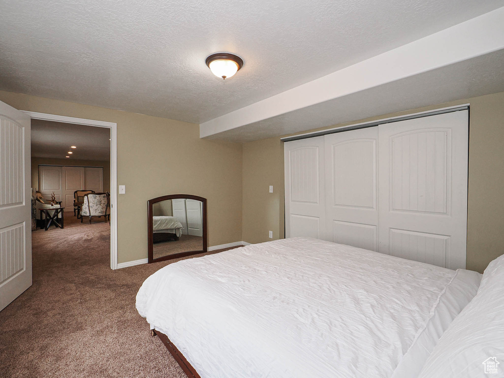 Bedroom with carpet, a closet, a textured ceiling, and baseboards
