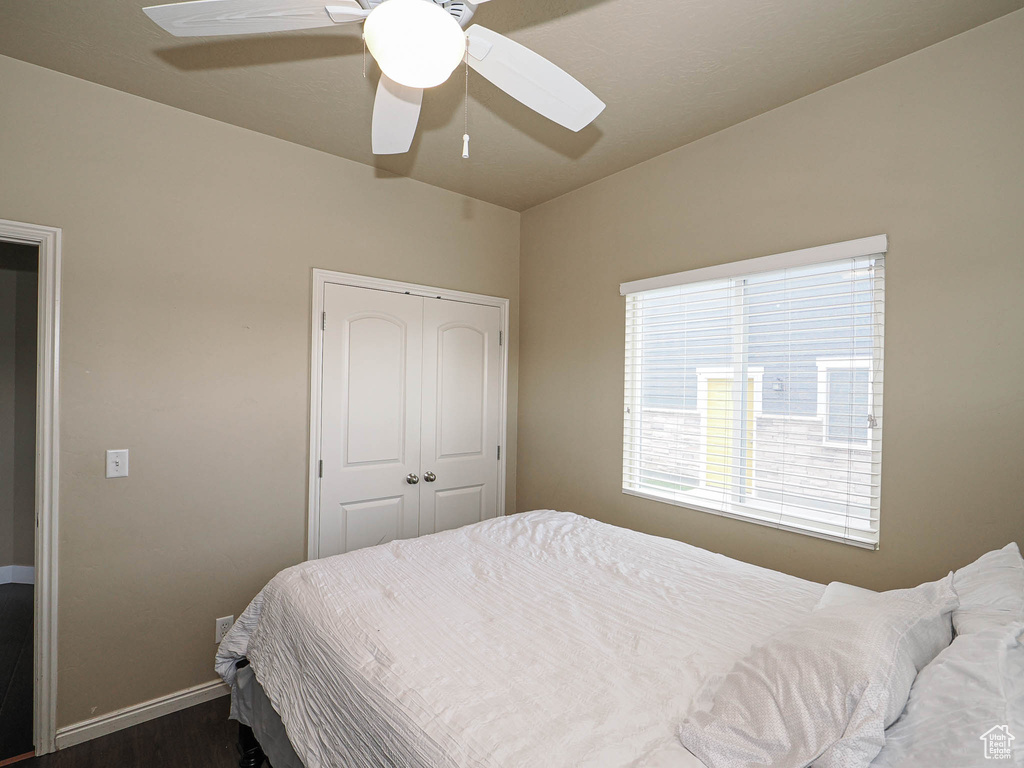 Bedroom with dark wood-type flooring, baseboards, a closet, and a ceiling fan