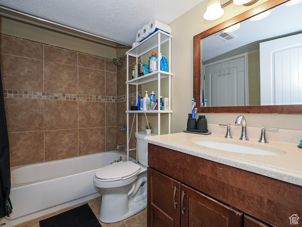 Bathroom with tub / shower combination, toilet, vanity, tile patterned floors, and a textured ceiling