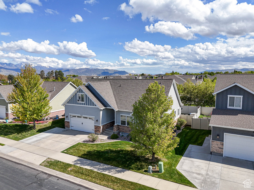 Craftsman house with stone siding, driveway, a shingled roof, a garage, and a mountain view