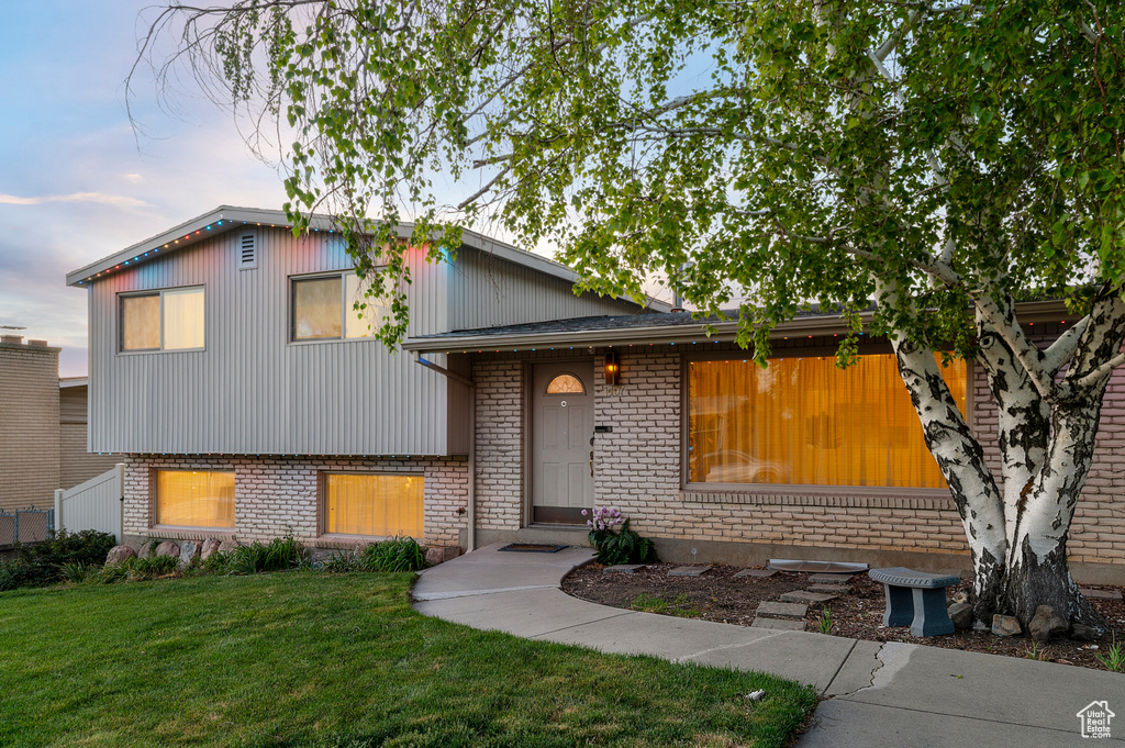 Tri-level home with a front yard and brick siding