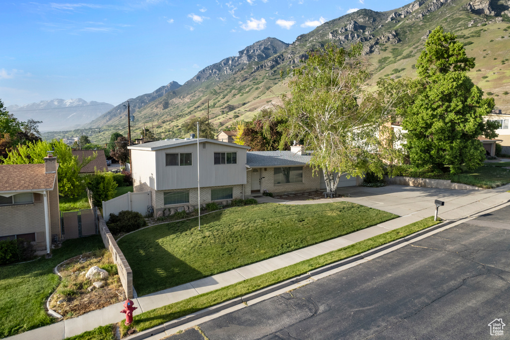 Tri-level home with a mountain view, concrete driveway, brick siding, and a chimney