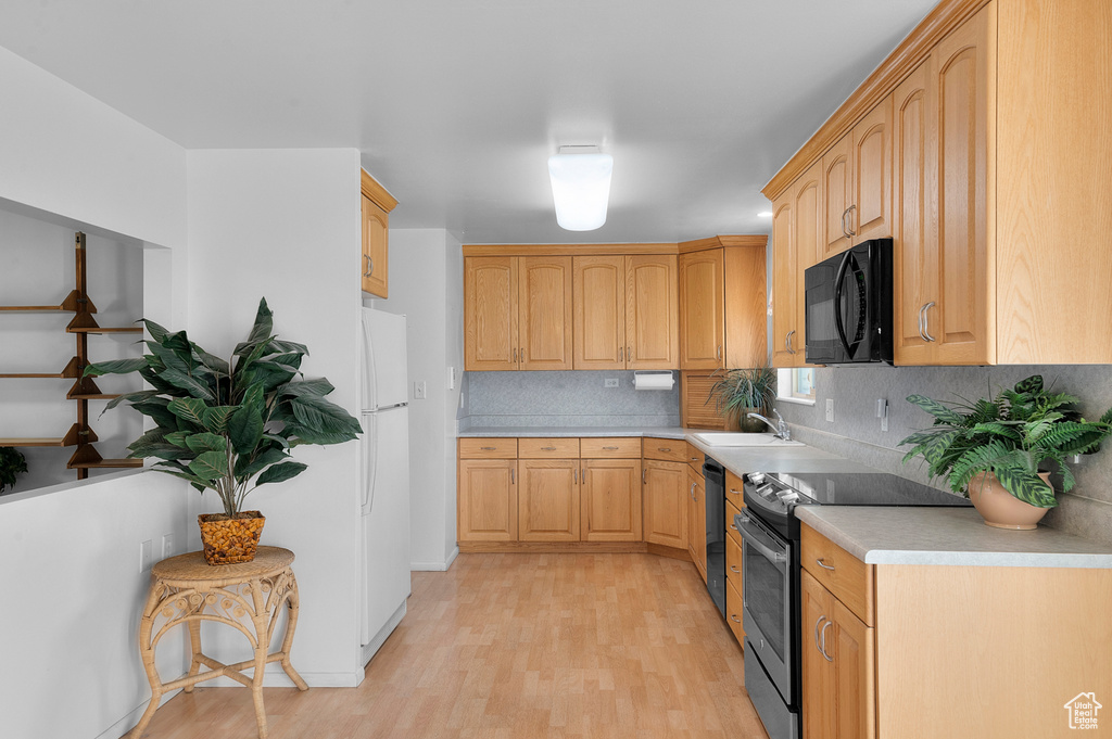 Kitchen featuring black appliances, light countertops, light brown cabinetry, and light wood-style flooring
