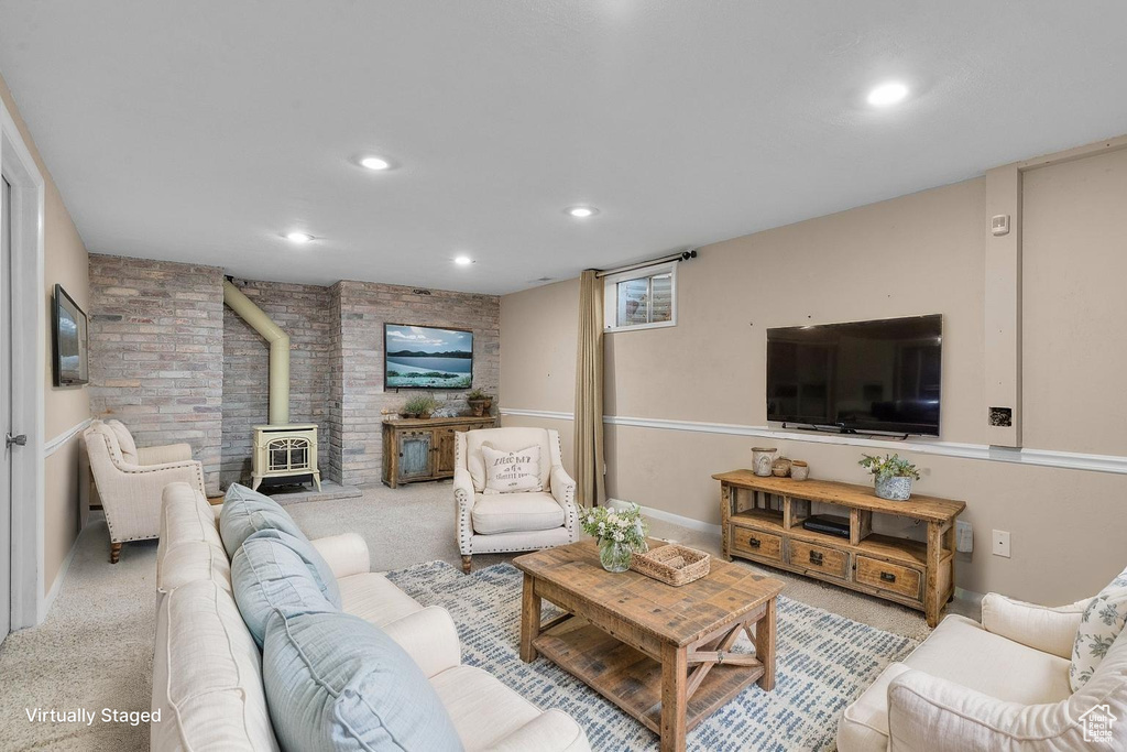 Carpeted living area featuring a wood stove, brick wall, and recessed lighting