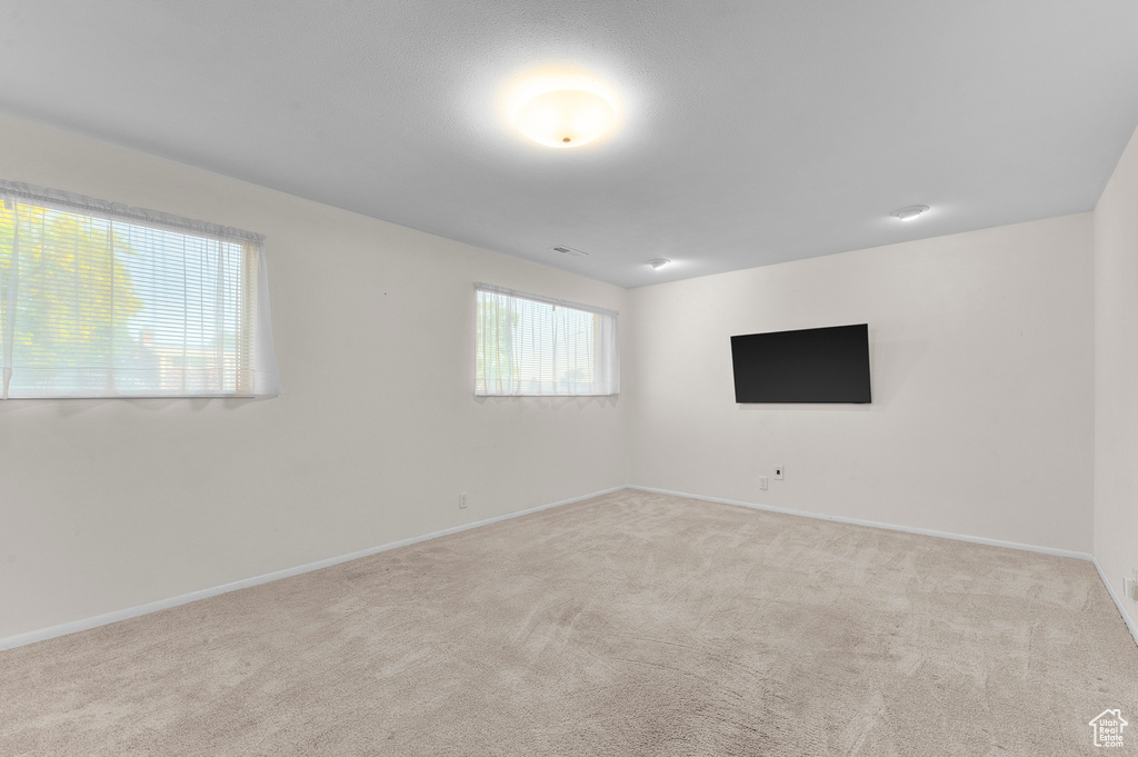 Carpeted spare room featuring baseboards