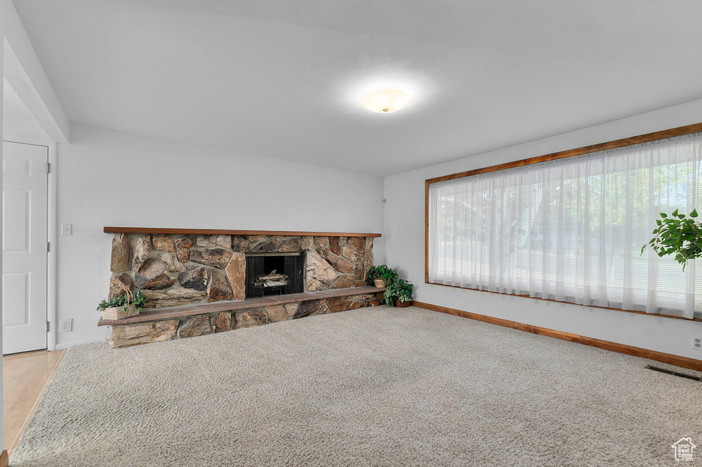Unfurnished living room featuring healthy amount of natural light, baseboards, and a fireplace