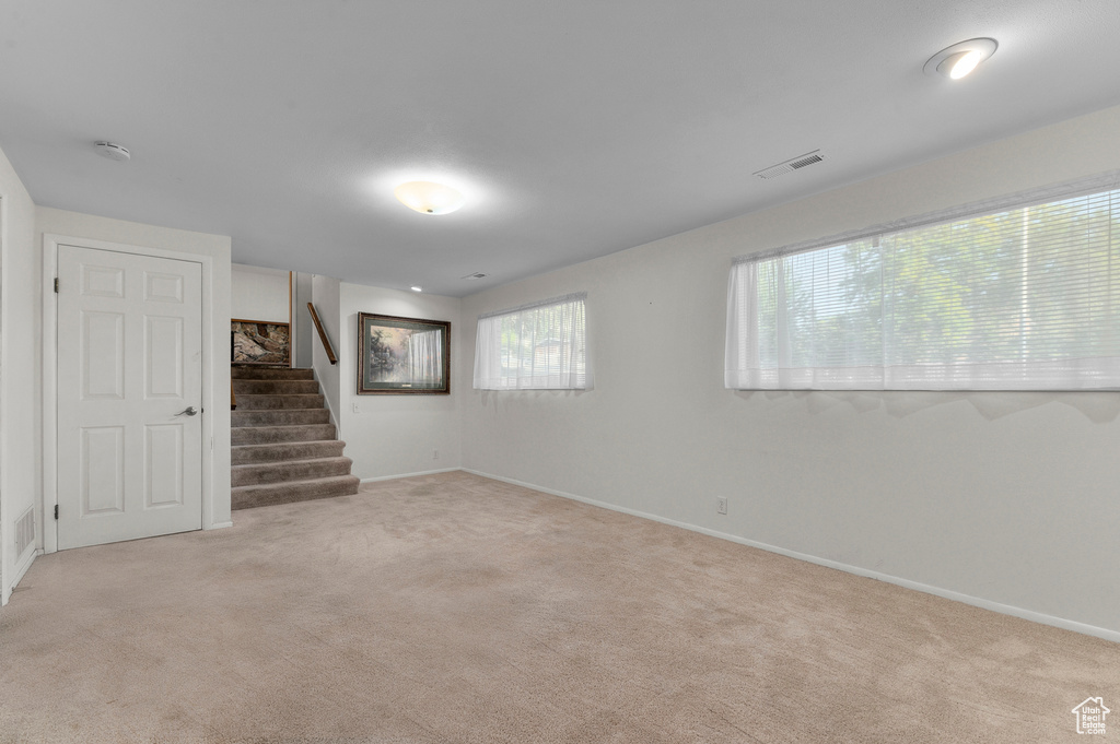 Below grade area with light colored carpet, stairs, and baseboards