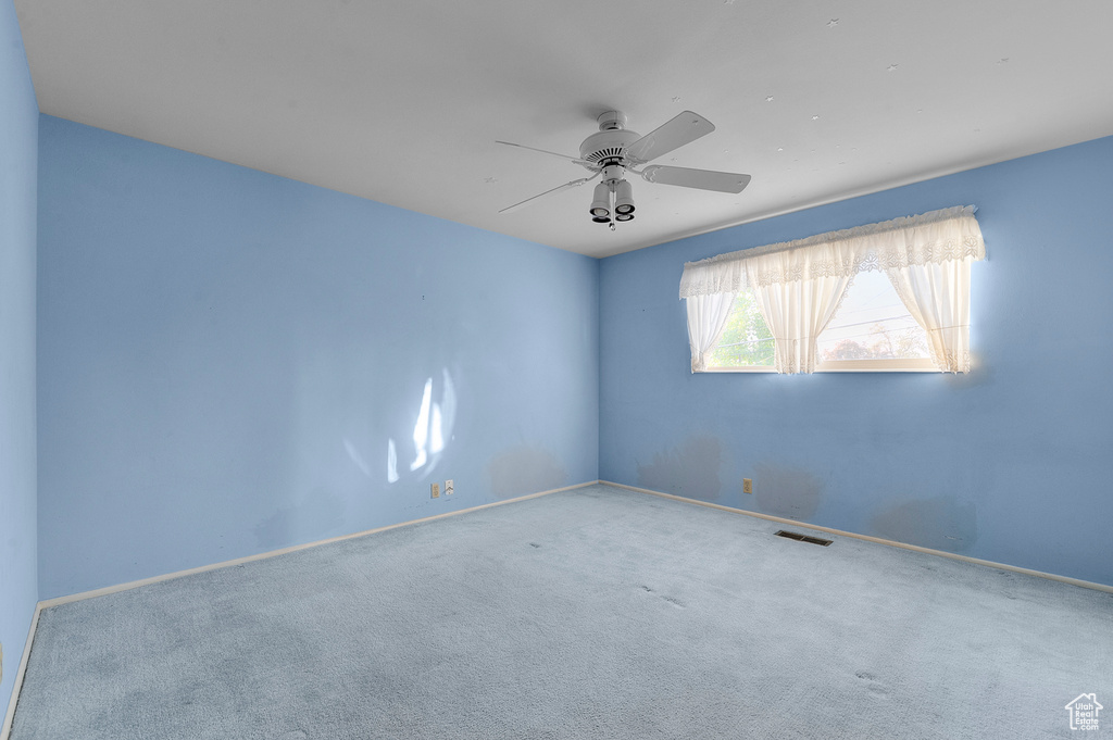 Carpeted spare room with ceiling fan and baseboards