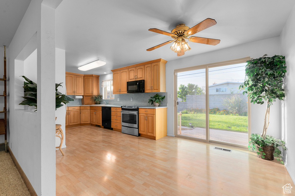 Kitchen with black appliances, light countertops, backsplash, light wood-style floors, and ceiling fan
