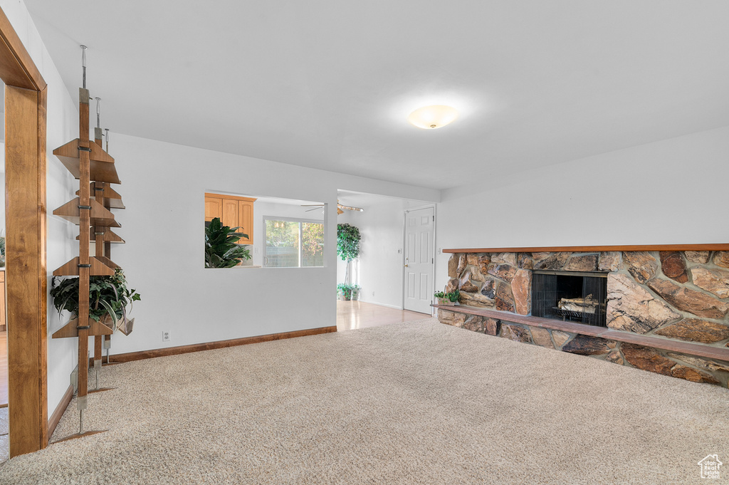 Unfurnished living room with carpet, a fireplace, and baseboards