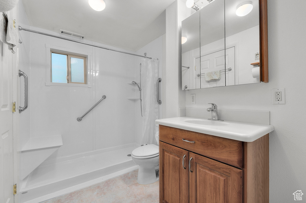 Bathroom featuring a stall shower, toilet, vanity, and tile patterned flooring