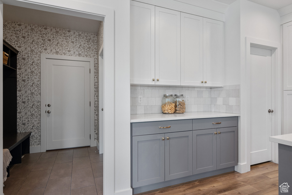 Kitchen with gray cabinets, wallpapered walls, light countertops, decorative backsplash, and white cabinets