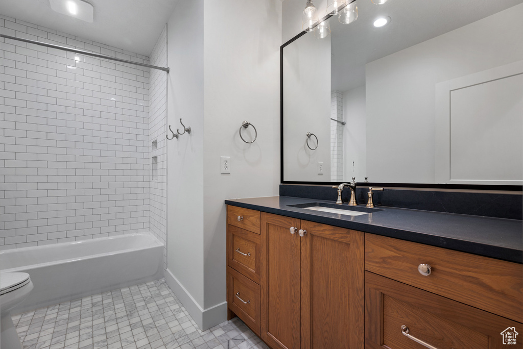 Bathroom featuring vanity, toilet, baseboards, and  shower combination
