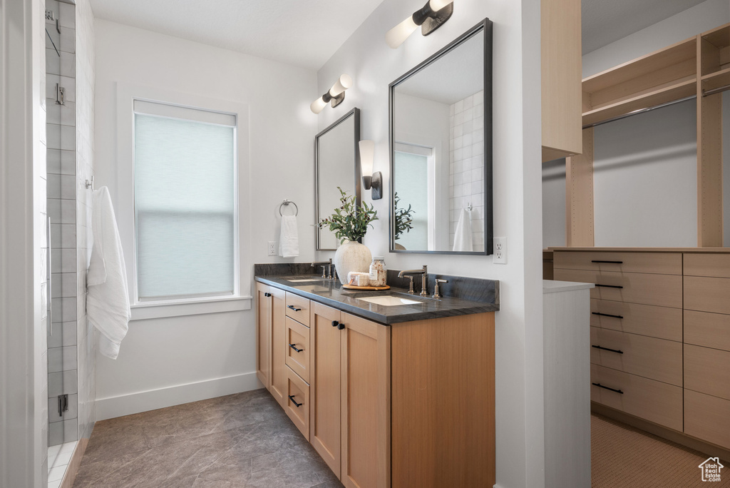 Full bathroom featuring double vanity and baseboards