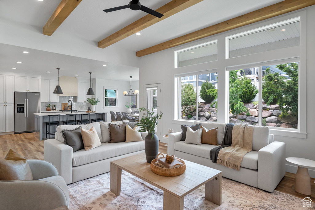 Living area featuring light wood-style floors, recessed lighting, healthy amount of natural light, beam ceiling, and a ceiling fan