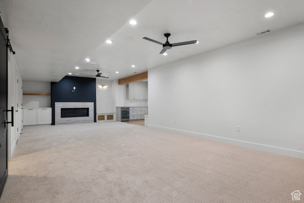 Unfurnished living room with ceiling fan, recessed lighting, light carpet, a glass covered fireplace, and baseboards