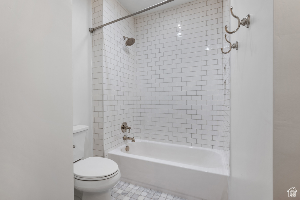 Bathroom featuring toilet, shower / bathtub combination, and tile patterned floors