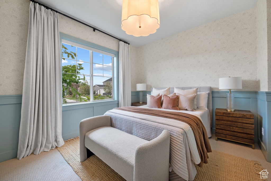 Bedroom featuring wallpapered walls and a wainscoted wall