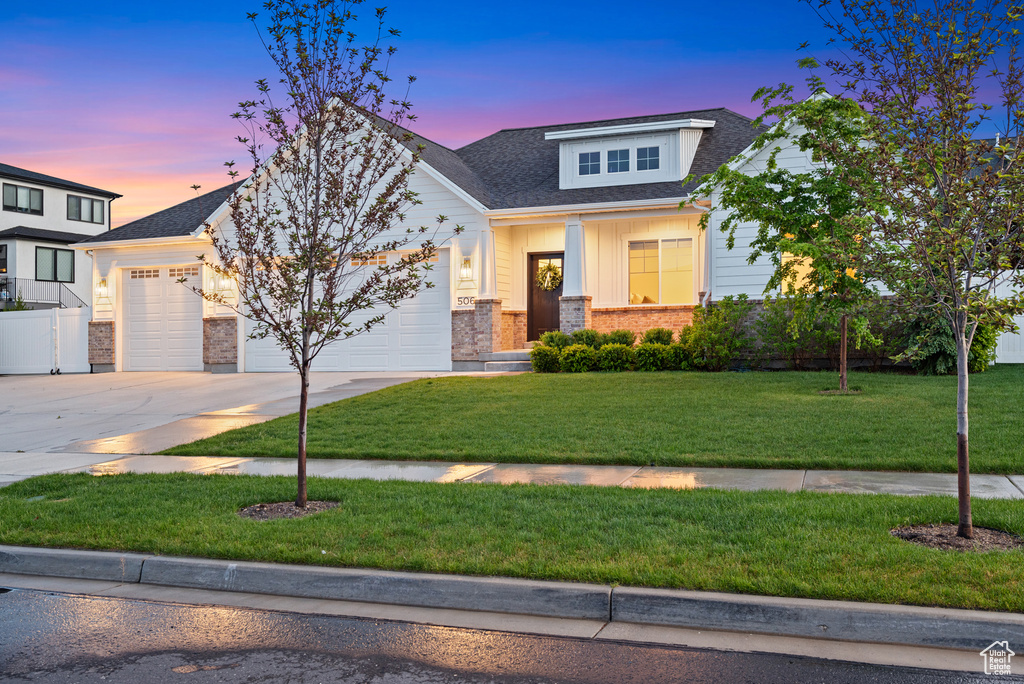 View of front of house featuring a garage, driveway, a front yard, brick siding, and roof with shingles