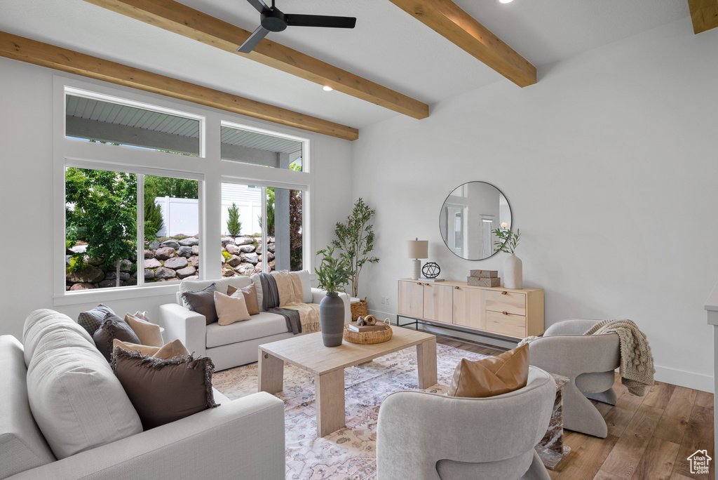 Living area featuring wood finished floors, beam ceiling, a ceiling fan, and baseboards
