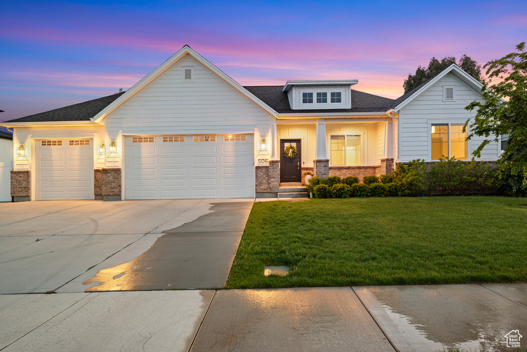 View of front facade with a garage, driveway, a front lawn, and brick siding