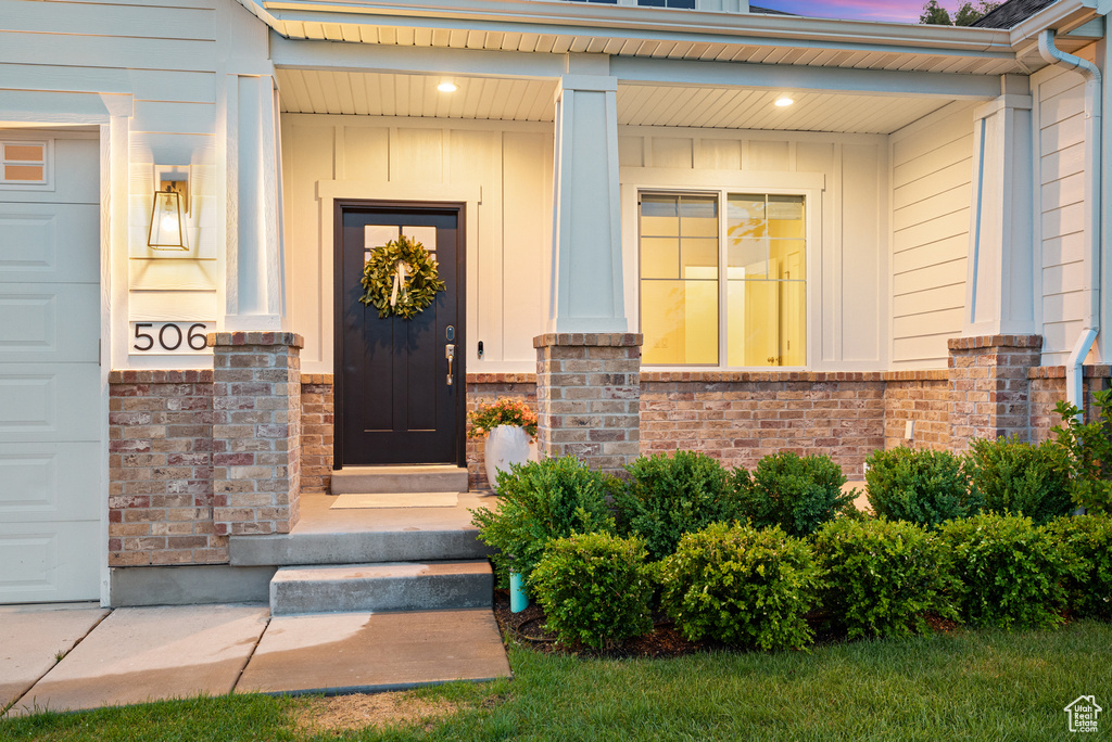 Property entrance featuring board and batten siding, covered porch, and brick siding