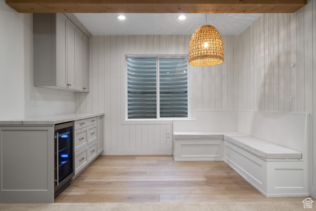 Unfurnished dining area with wine cooler, light wood-style flooring, and recessed lighting