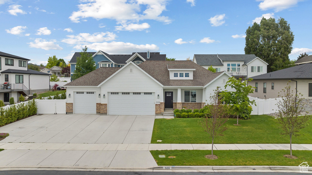 View of front of house featuring an attached garage, a residential view, concrete driveway, a shingled roof, and brick siding