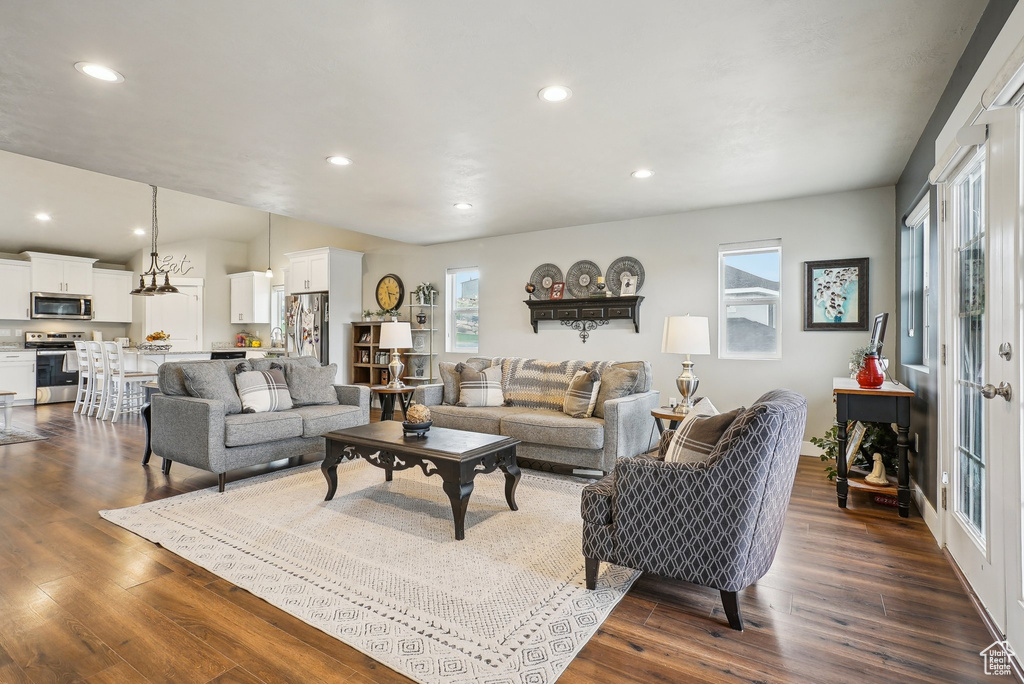 Living room with healthy amount of natural light, dark wood-style floors, and recessed lighting