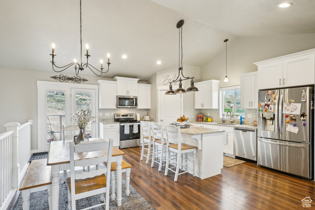 Kitchen featuring appliances with stainless steel finishes, a sink, a kitchen island, a kitchen breakfast bar, and white cabinetry