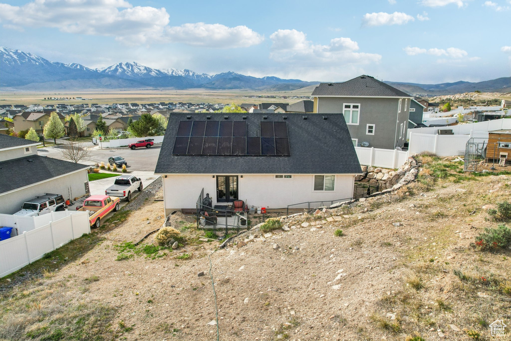 Back of property with french doors, solar panels, a mountain view, and a fenced backyard