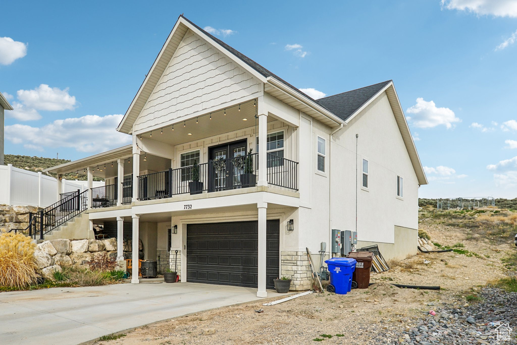 View of front of property with driveway, a balcony, an attached garage, and stucco siding