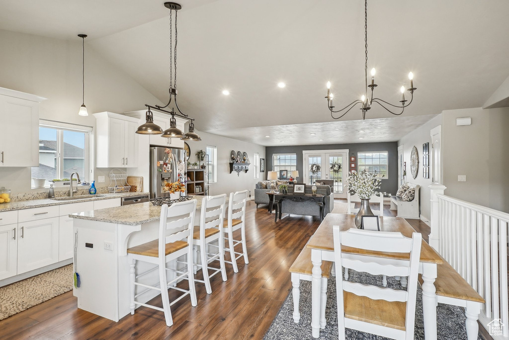 Kitchen with stainless steel refrigerator with ice dispenser, a sink, a kitchen island, dark wood-type flooring, and white cabinetry
