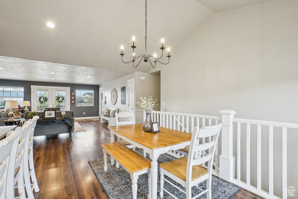 Dining room with dark wood-style floors, vaulted ceiling, a chandelier, and recessed lighting