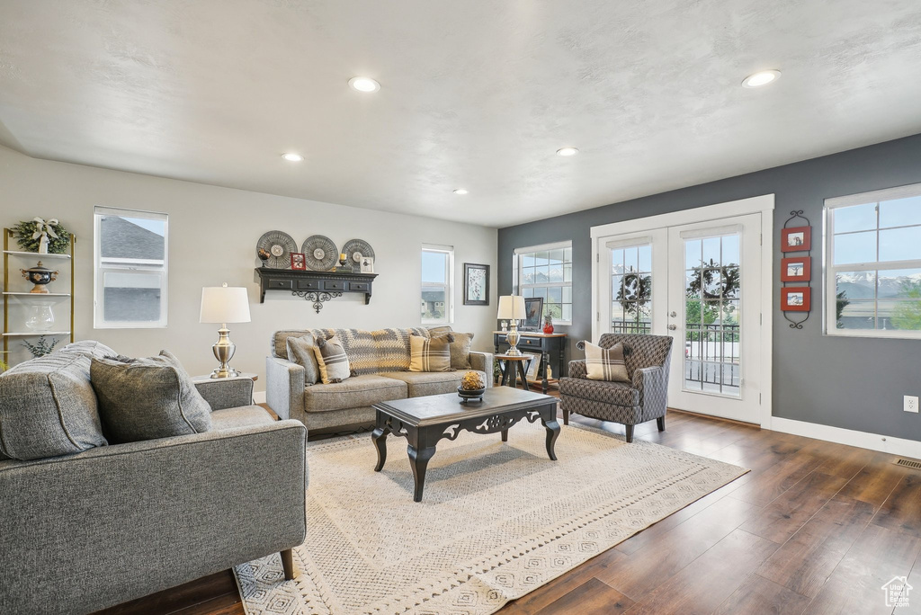 Living room with plenty of natural light, recessed lighting, dark wood-type flooring, baseboards, and french doors