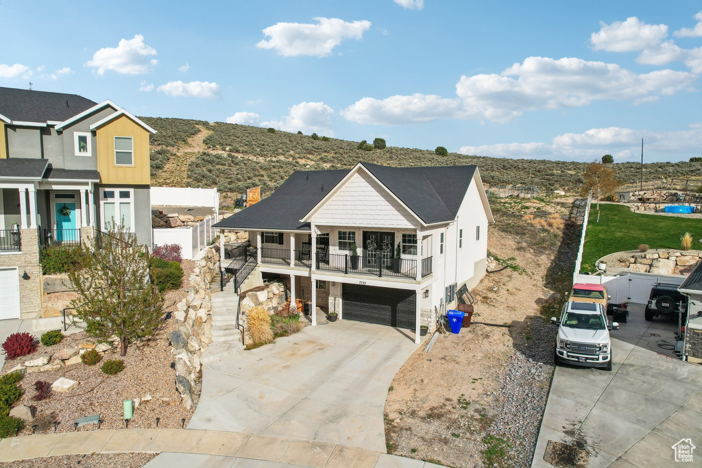 View of front of property featuring a garage, a balcony, driveway, and stairway