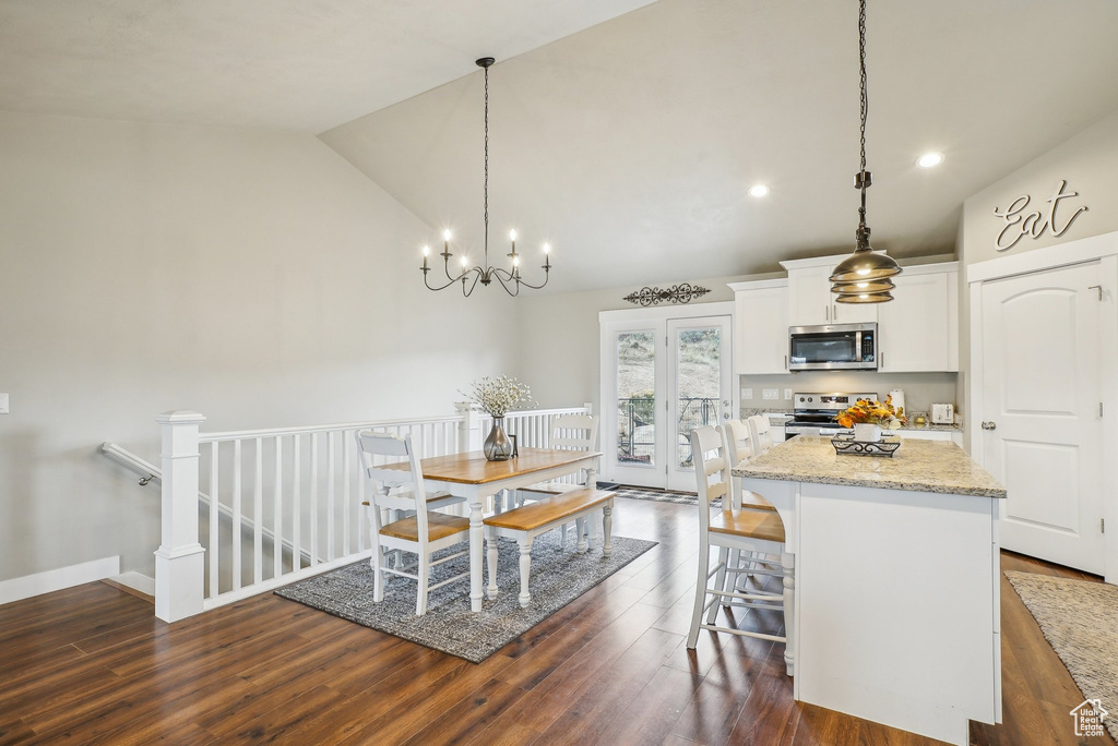 Kitchen with stainless steel appliances, a center island, white cabinets, dark wood-style floors, and a kitchen bar