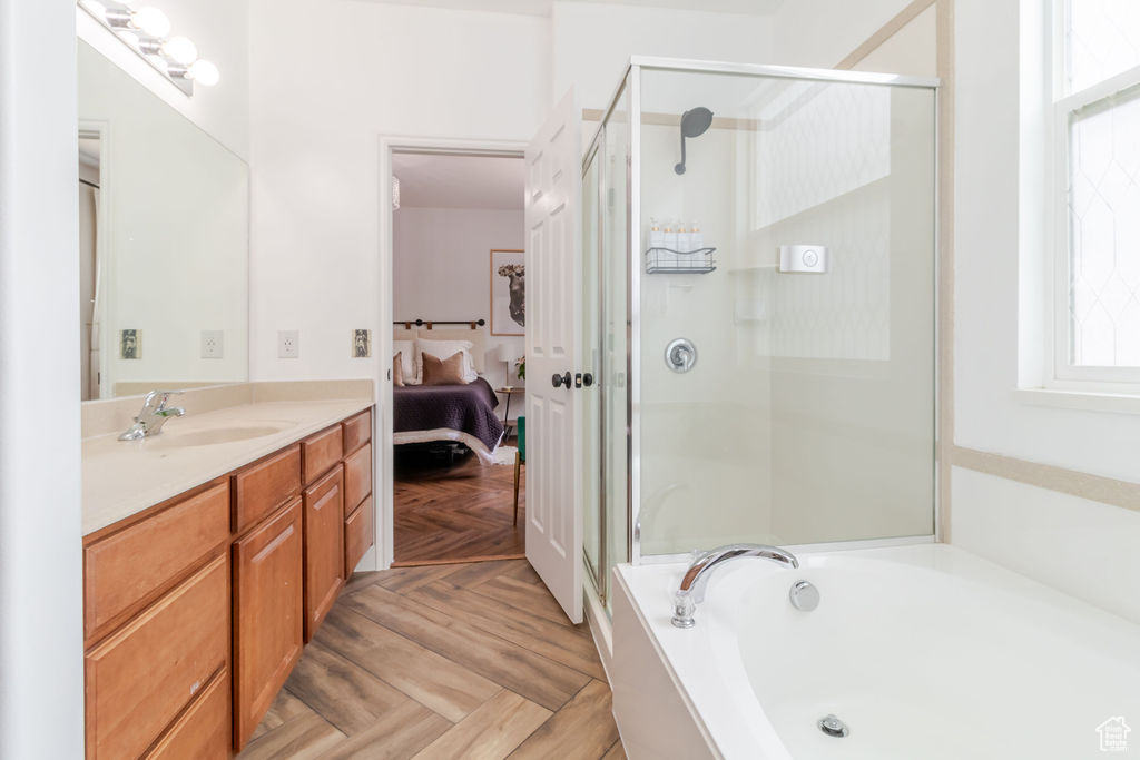 Full bathroom with a shower stall, vanity, a garden tub, and healthy amount of natural light